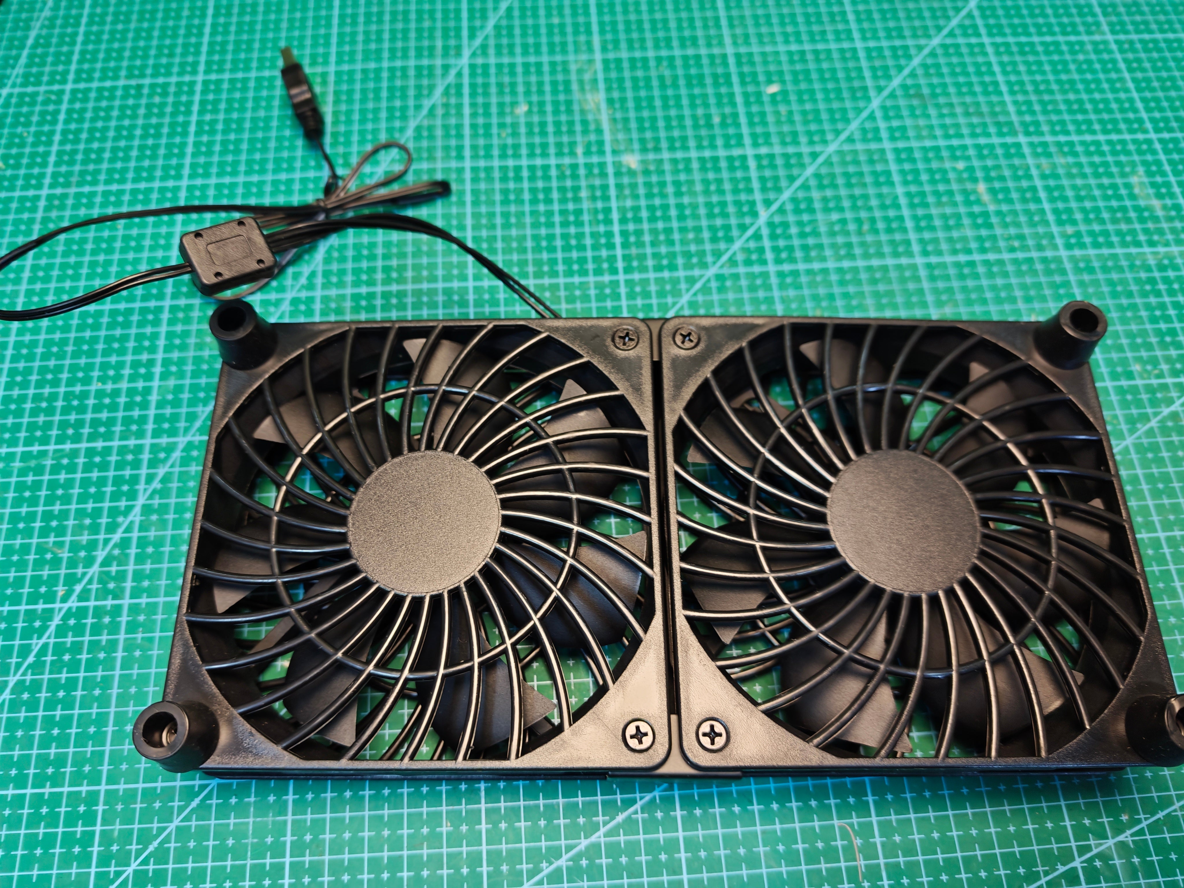 Complete rear view of the black dual USB cooling fan unit with protective grilles and raised feet